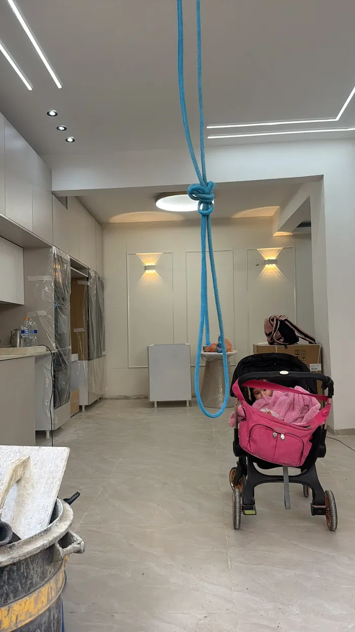 דירה מיושבת בשלב השיפוץ עם עגלת תינוק בחדר.
