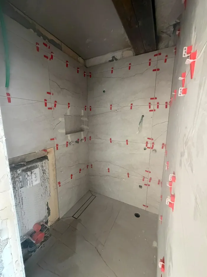 חדר רחצה מפורק עם סימונים על הקירות לפני חידוש האינסטלציה והחיפוי.