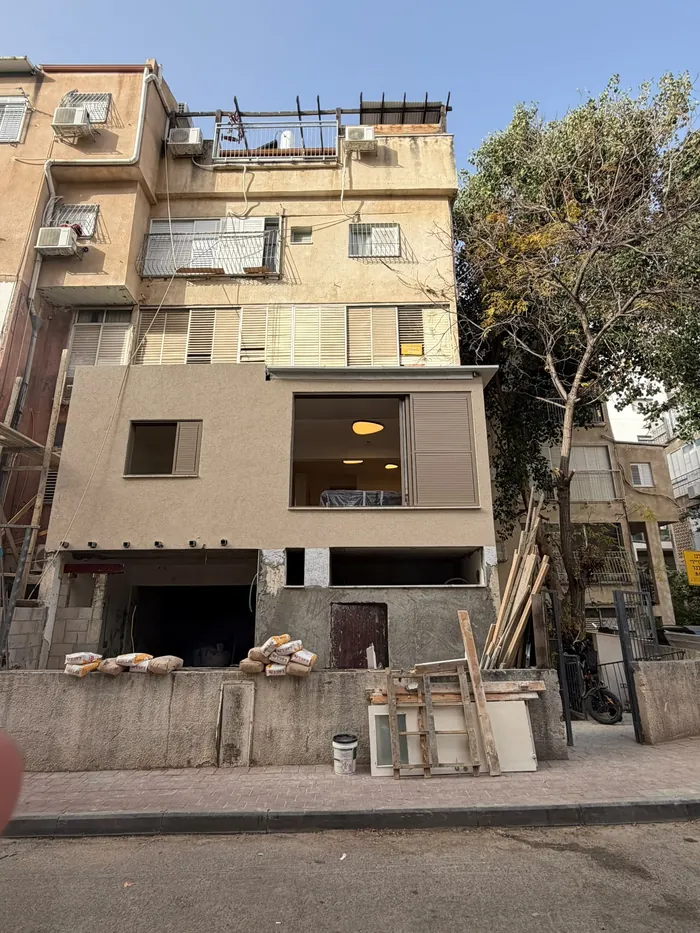 חזית בניין מגורים עם עבודות שיפוץ ומנוף.