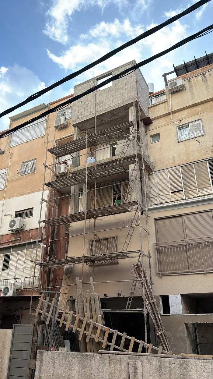 בניין מגורים בעבודות חזית עם פיגום על מספר קומות.