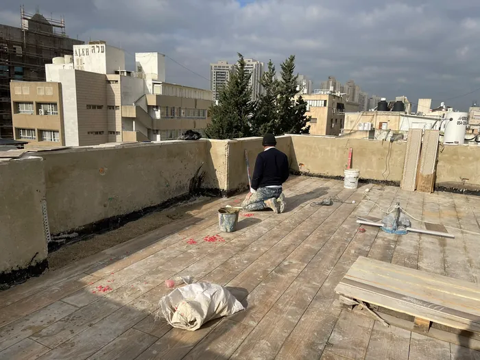 עבודות איטום וריצוף על גג בניין עם נוף לעיר.